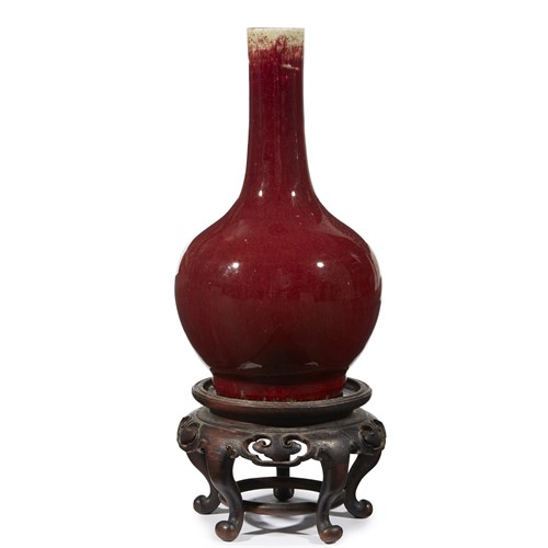 Lot 153 - A Chinese copper red-glazed bottle vase with carved wood stand