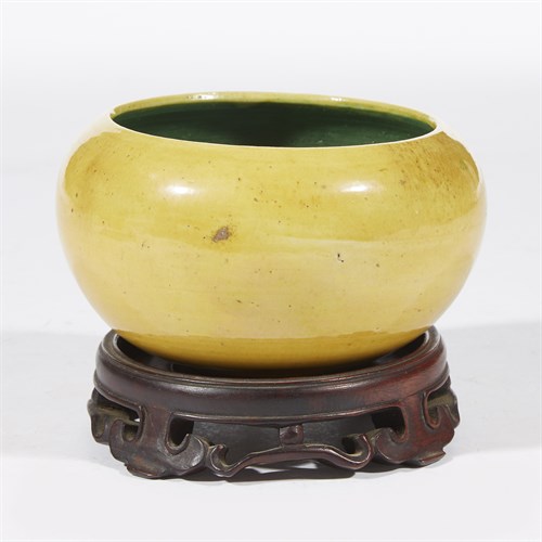 Lot 140 - A Chinese yellow and green-enameled "alms bowl" with associated wood stand