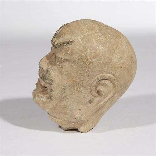 Lot 31 - A carved and painted stone head of a guardian warrior