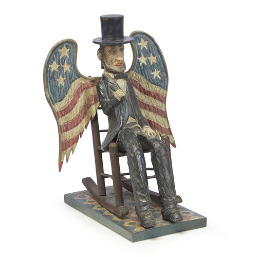 Lot 85 - Carved and painted figure of a seated Abraham Lincoln with American flag painted wings