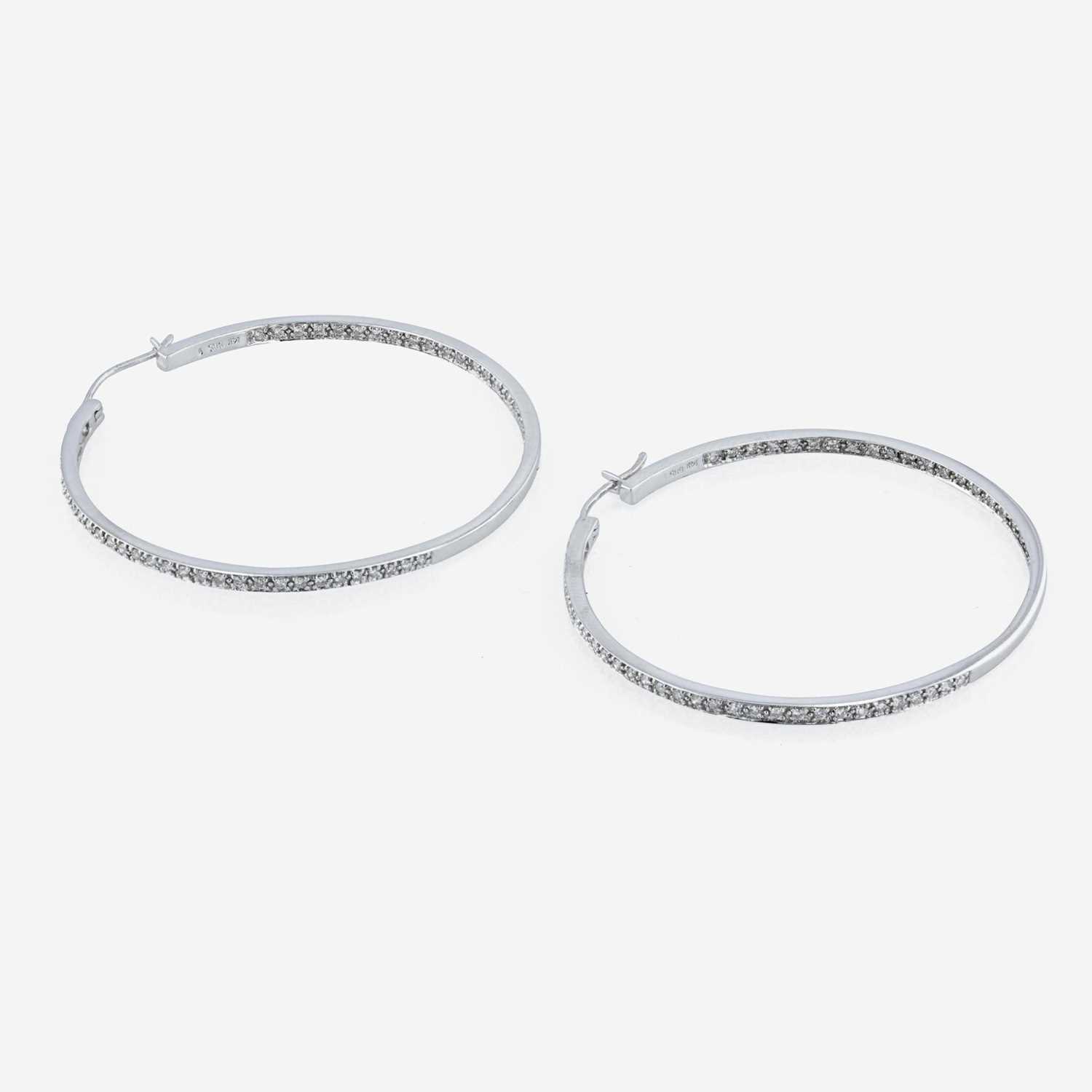 Lot 59 - A pair of 14K white gold and diamond hoop earrings