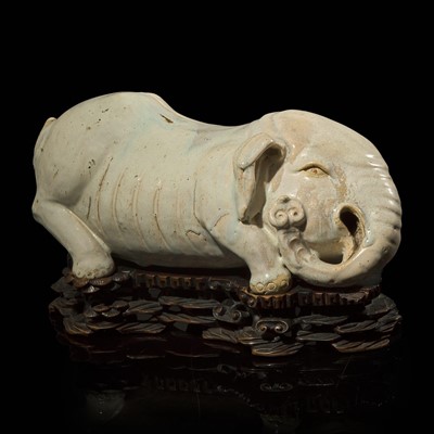 Lot 83 - An unusual Chinese elephant-form white-glazed stoneware pillow and carved wood base 白象瓷枕與木座