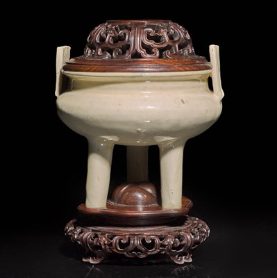 Lot 84 - A Chinese creamy-white gazed tripod censer with finely carved wood cover and matching stand 白瓷香爐配木座